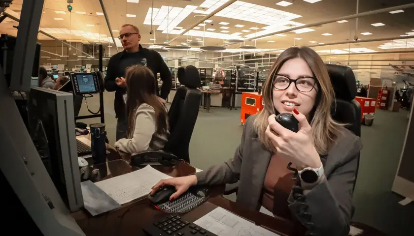 Kontroler ruchu lotniczego w akcji, monitoruje przestrzeń powietrzną i komunikuje się przez radio.