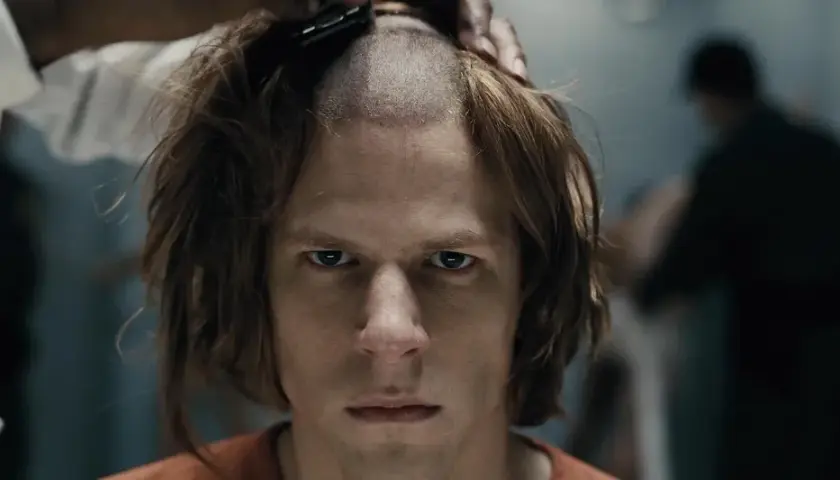 Un primo piano intenso di Jesse Eisenberg in un film, mentre gli rasano i capelli.