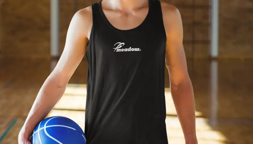Gracz w czarnej koszulce z logo "Meadow" trzyma niebieską piłkę do koszykówki. Idealny do gry w koszykówkę 3x3, zasady tej dynamicznej odmiany sportu są proste i angażujące.