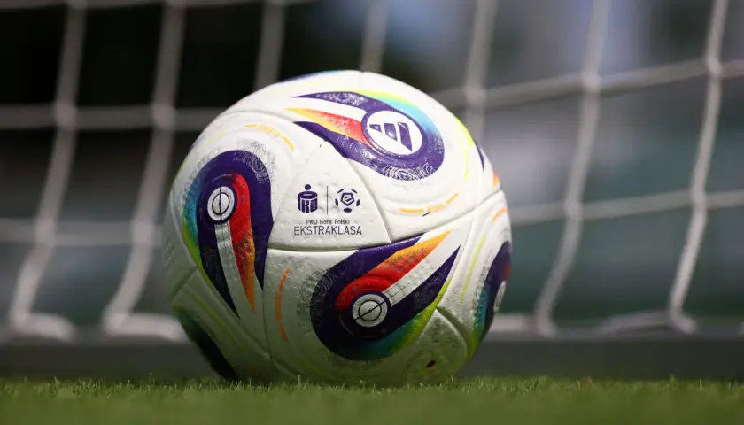 Piłka nożna PKO BP Ekstraklasa na trawie przed bramką.