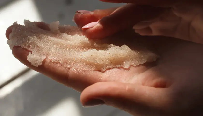 Dłonie trzymające domowy peeling cukrowy. Delikatne drobinki kuszą do domowego SPA.