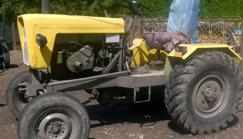 Żółty, domowej roboty traktor, który wygląda jakby ktoś chciał zobaczyć jak zrobić ciągnik sam.