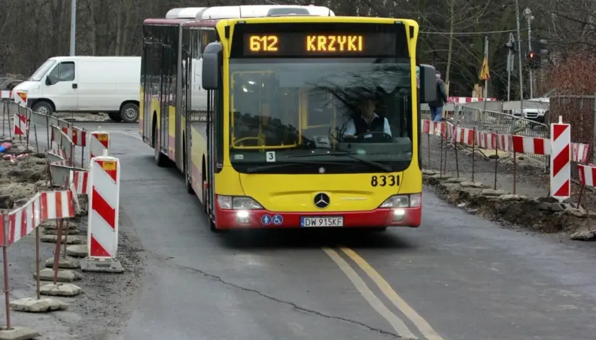 Autobus MPK linii 612 z napisem "KRZYKI" jedzie po drodze z robotami drogowymi. Jak dojechać na Bielany Wrocławskie MPK? Ten autobus może być odpowiedzią.