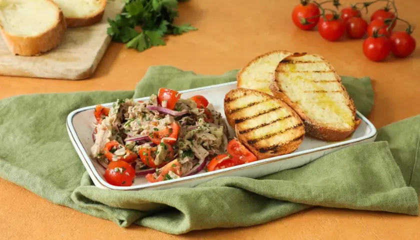 Deliziosa insalata di bollito con pomodorini, cipolla rossa e pane abbrustolito, un piatto fresco e saporito.