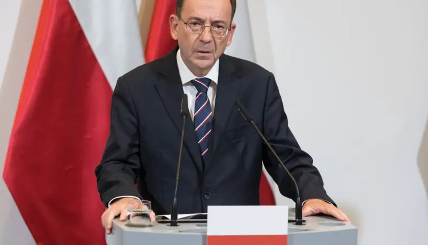 Mężczyzna w garniturze przy mównicy z polską flagą. Czy to odpowiedź na pytanie, dlaczego prezydent nie skorzystał z prawa łaski wobec skazanych urzędników państwowych?