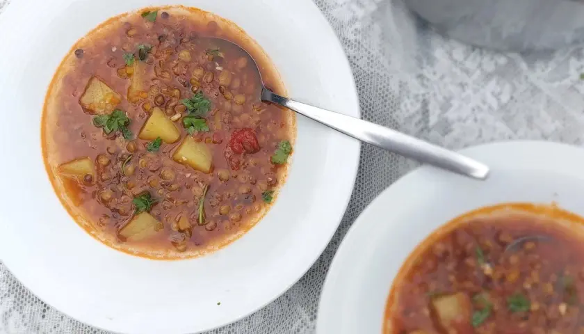 Herzhafte italienische Linsensuppe mit Kartoffeln und Kräutern in weißen Schalen, bereit zum Genießen.