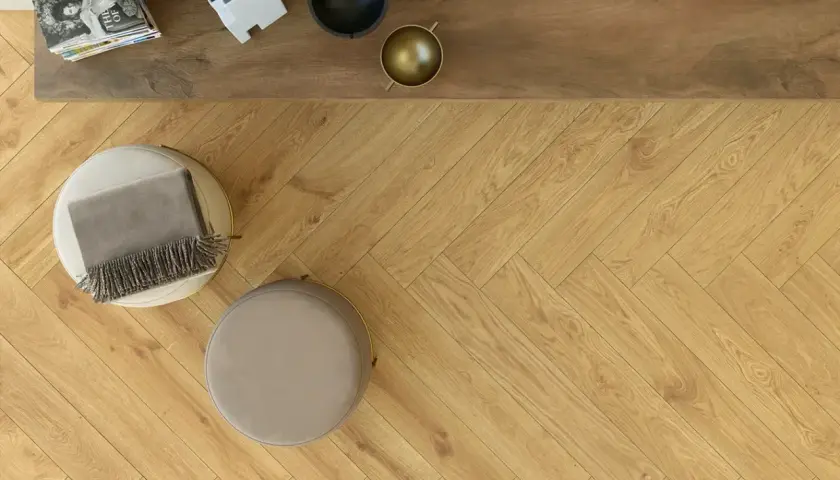Posa pavimento gres effetto legno a spina di pesce, con pouf e coperta.