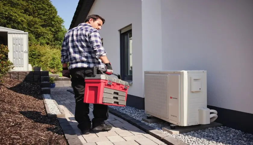 Technik z walizką narzędziową przy pompie ciepła. Regularny przegląd pompy ciepła zapewnia jej sprawność.