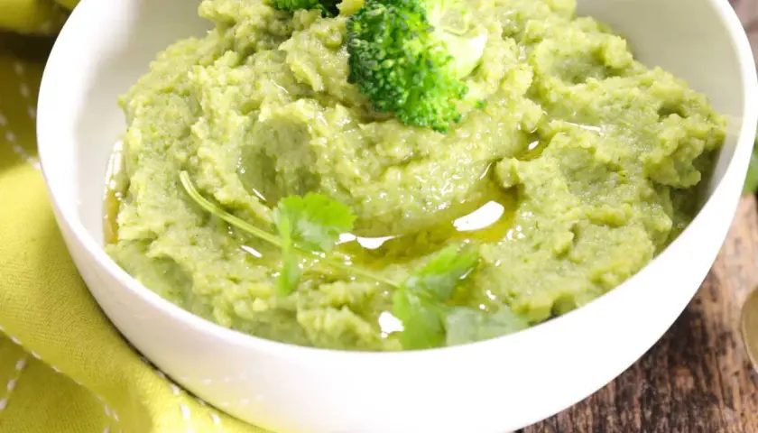 Un bol de purée de brocolis onctueuse, garnie de fleurettes de brocolis et d'un filet d'huile d'olive. Une touche de verdure pour un plat sain.