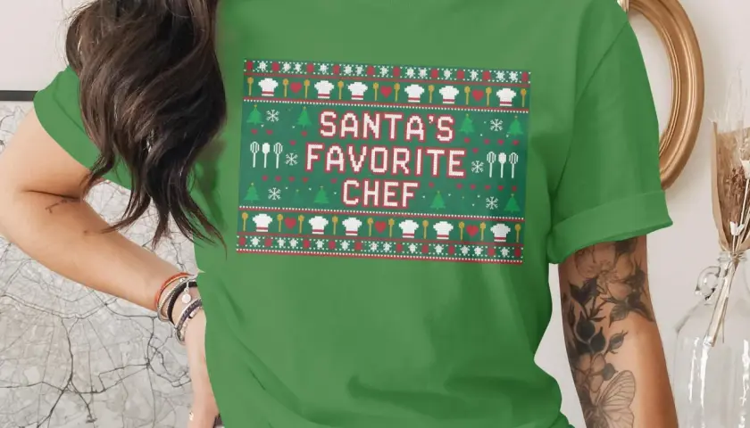 Grünes T-Shirt mit Weihnachtsmuster und der Aufschrift "Santa's Favorite Chef".