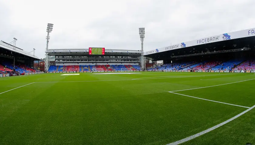 Zielona murawa stadionu Selhurst Park, trybuny w kolorach czerwonym i niebieskim, światła masztów.