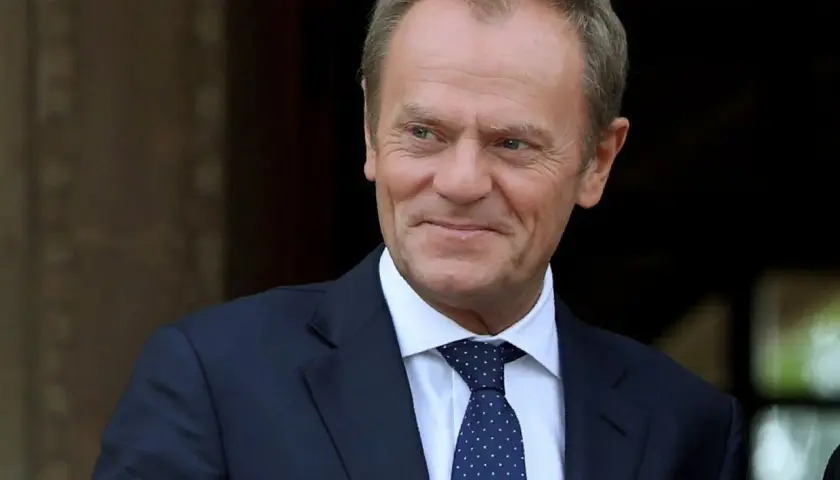 Donald Tusk w garniturze i krawacie, uśmiecha się.