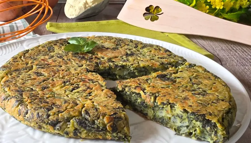 Frittata di spinaci dorata e soffice, guarnita con basilico fresco, pronta per essere gustata. Ingredienti freschi sullo sfondo.