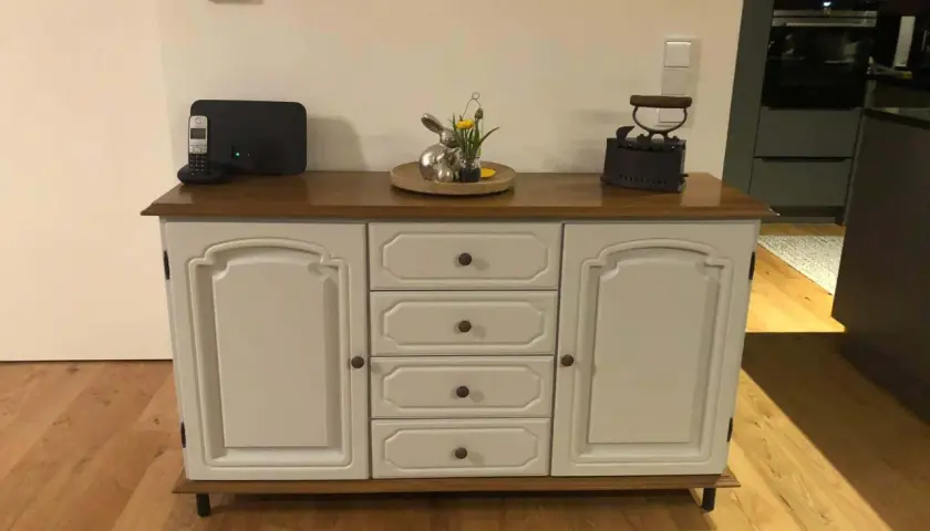 Ein Sideboard mit Eichenholzplatte, das rustikal und modern kombiniert. Darauf ein Osterhase, ein Bügeleisen und ein Telefon.