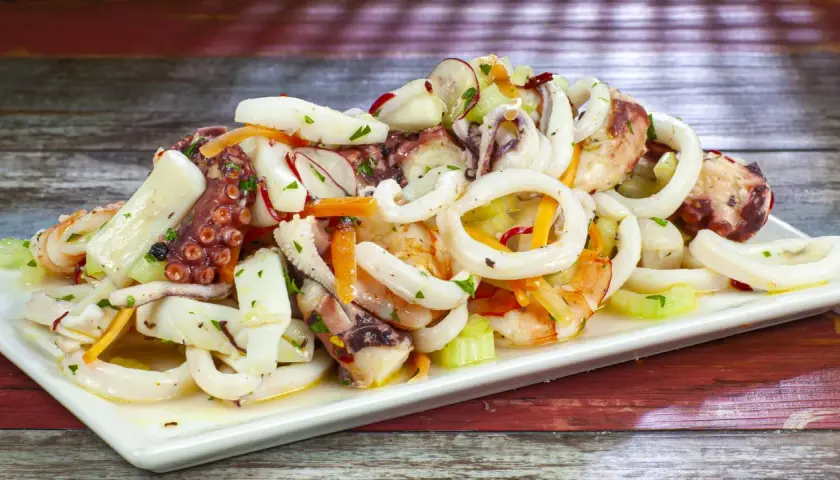Deliziosa insalata di mare con anelli di calamaro, tentacoli di polpo e gamberi, condita con verdure fresche.