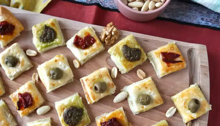 Pyszne przekąski francuskie z oliwkami, pesto i suszonymi pomidorami, ułożone na desce.