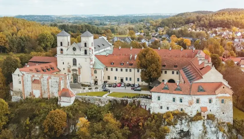 Najstarszy klasztor w Polsce, benedyktyńskie opactwo na skale, otoczone jesiennymi drzewami.