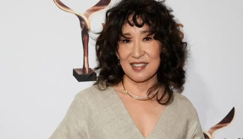 Sandra Oh med en snygg frisyr med halvlångt hår uppklippt i mjuka vågor. Hon bär en beige klänning och ett glittrande halsband.
