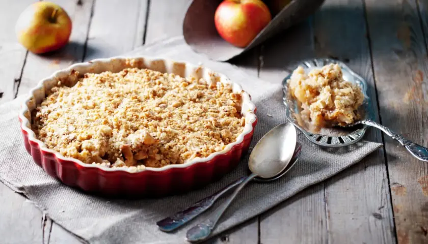 Un délicieux crumble pomme tout juste sorti du four, prêt à être dégusté. Des pommes fondantes sous une couche croustillante.