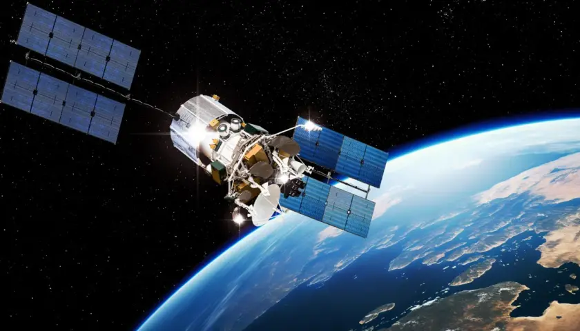 Satelita z dużymi panelami słonecznymi krąży nad Ziemią. Widać jego skomplikowaną konstrukcję i antenę.