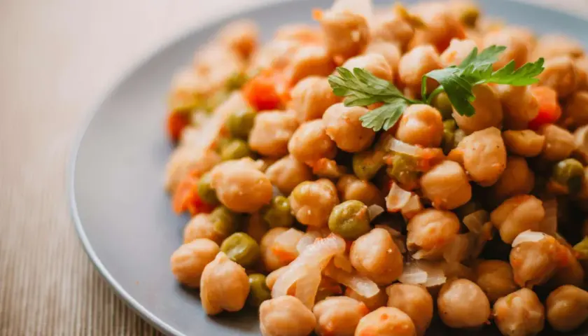 Plato de garbanzos guisados con guisantes y zanahoria, perfecto para una receta saludable.