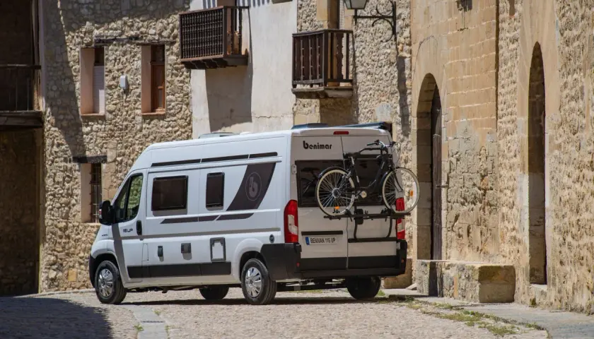Furgoneta blanca con portabicicletas trasero, mostrando cómo llevar la bici dentro de la furgoneta para aventuras.