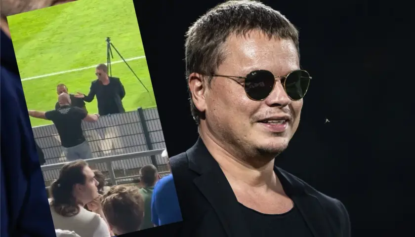 Właściciel Wisły Kraków w okularach przeciwsłonecznych, na tle fragmentu stadionu i kibiców.