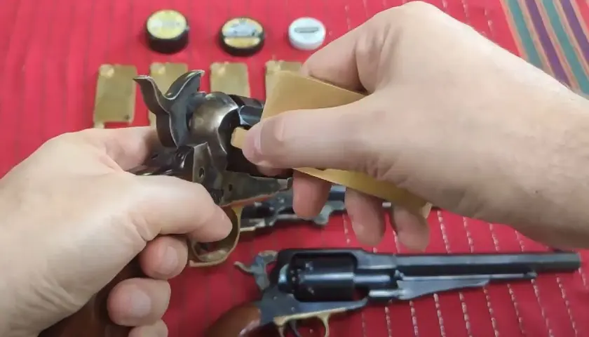 Dłonie przygotowują rewolwer do strzału, używając kapiszonów Remington No. 10.