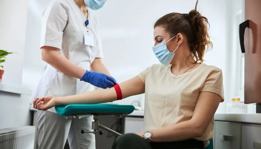 Pielęgniarka przygotowuje pacjentkę do pobrania krwi. Badanie może pomóc zdiagnozować leukopenię, czyli zbyt niski poziom białych krwinek.