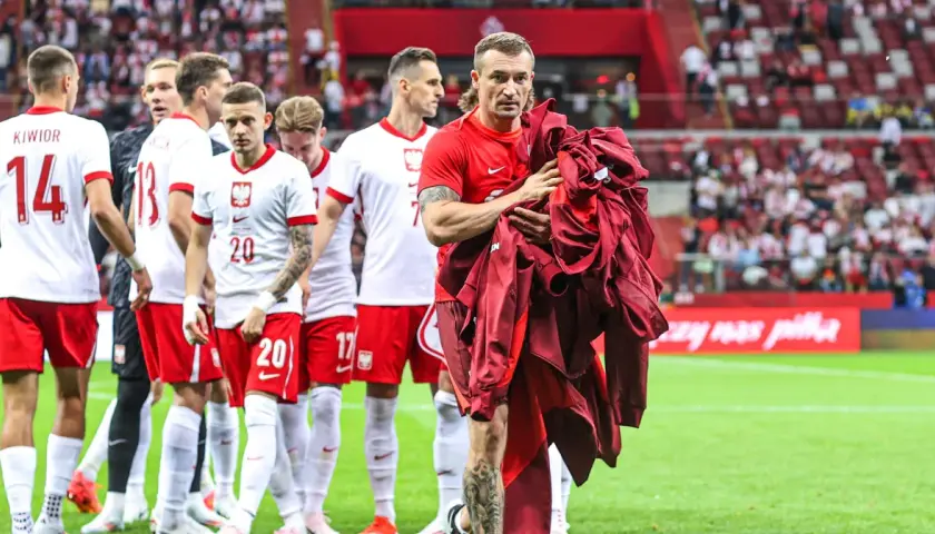 Piłkarze reprezentacji Polski schodzą z boiska. Na pierwszym planie Grzegorz Krychowiak, który trzyma w rękach bordową bluzę. Kim jest Krychowiak? To doświadczony pomocnik, który grał w wielu klubach.