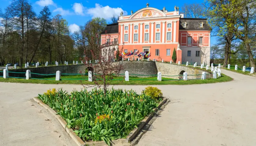 Kurozwęki atrakcje: barokowy pałac otoczony parkiem, z kwitnącymi tulipanami przed wejściem.