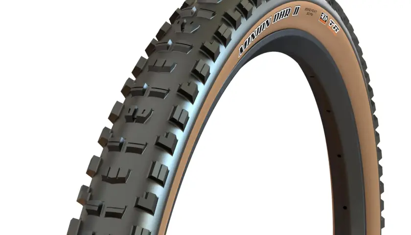 Close-up of a Maxxis Minion DHR II tire with tan sidewalls, ready for trail riding. Many riders praise these for their grip.