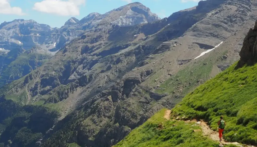 Senderista en un camino escarpado con vistas a las majestuosas montañas de Ordesa Monte Perdido.