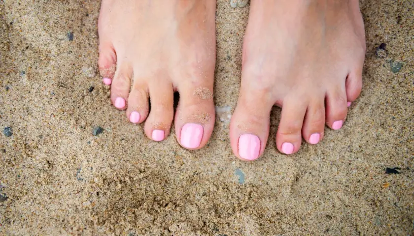 Stopy na piasku z różowym, modnym pedicure. Idealne na lato.