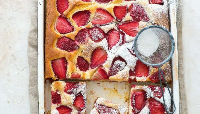 Le gâteau aux fraises de maman, doré et garni de fruits rouges, est saupoudré de sucre glace. Un délice !