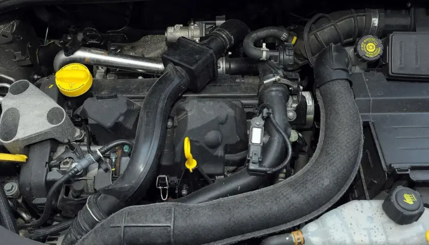 Silnik Renault Clio 3 z widocznymi przewodami, czujnikami i żółtym korkiem oleju.