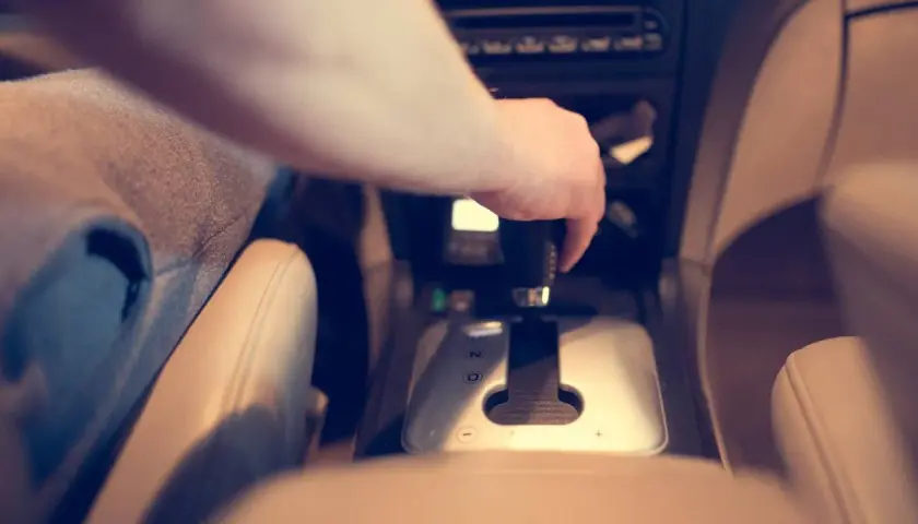 Dłoń kierowcy na dźwigni zmiany biegów. W samochodzie zainstalowana jest blokada alkoholowa, która wymaga dmuchnięcia przed jazdą.