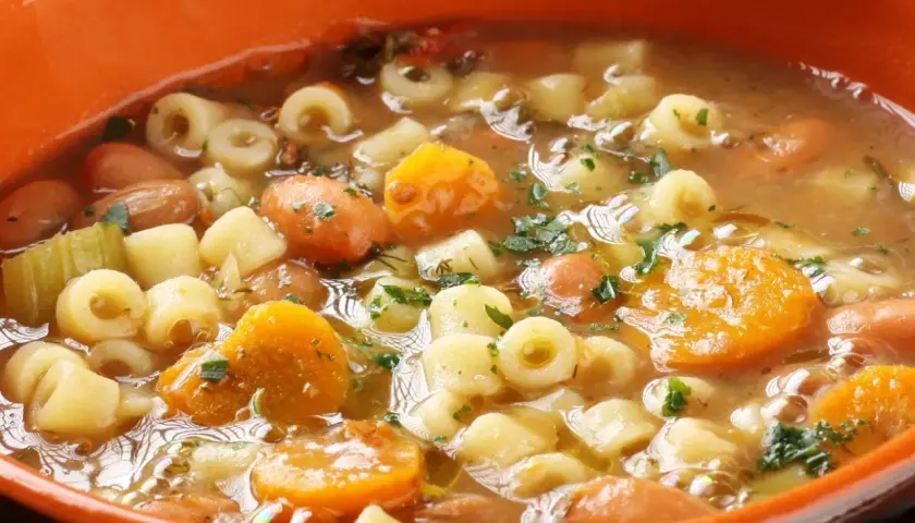 Gęsta, aromatyczna zupa minestrone z makaronem, fasolą, marchewką i ziemniakami, posypana natką pietruszki.