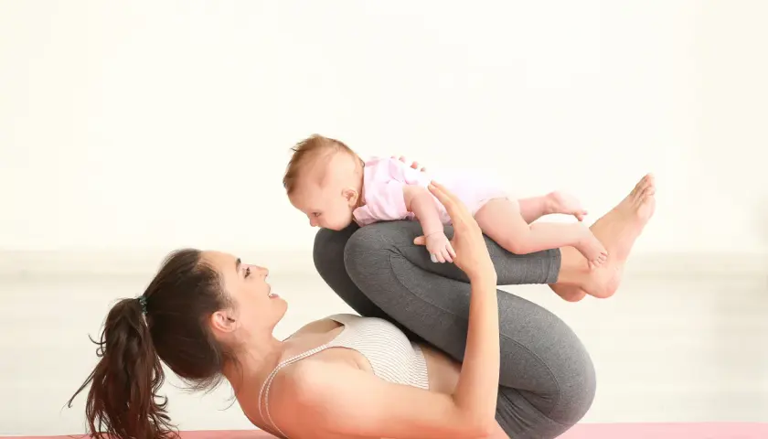 Mama ćwiczy z dzieckiem na macie. Połóg to czas na regenerację, ale i zabawę z maluchem.