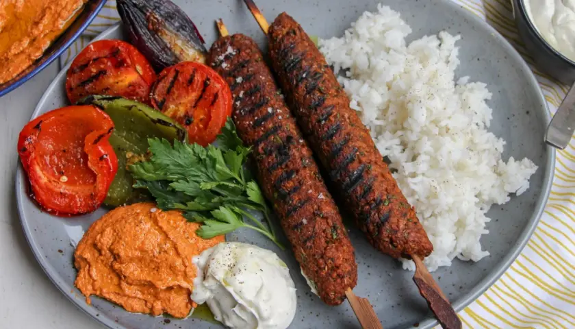 Saftiga kebabspett i ugn serveras med ris, grillade grönsaker och en krämig röra. En härlig måltid!