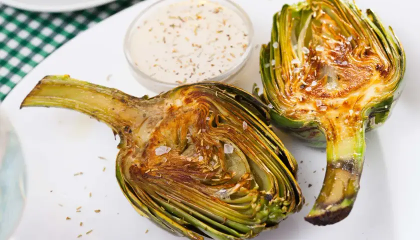 Alcachofas gratinadas con queso, tiernas y doradas, listas para disfrutar con una cremosa salsa.