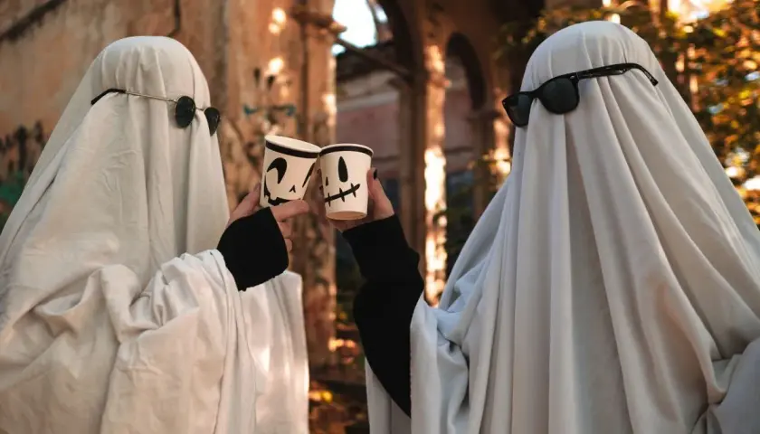 Dwa duchy w okularach przeciwsłonecznych wznoszą kubki z dyniami. Prosty strój, jak zrobić strój Hefajstosa, ale na Halloween!