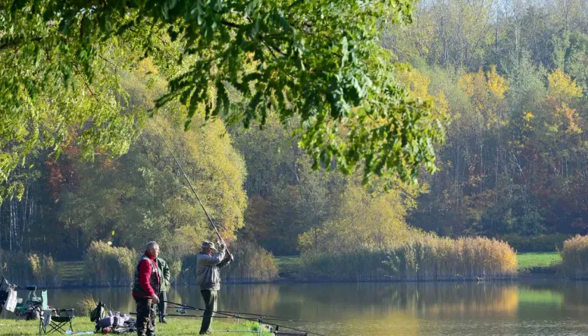 Wędkarze nad jednym z **trzech stawów** w jesiennej scenerii.