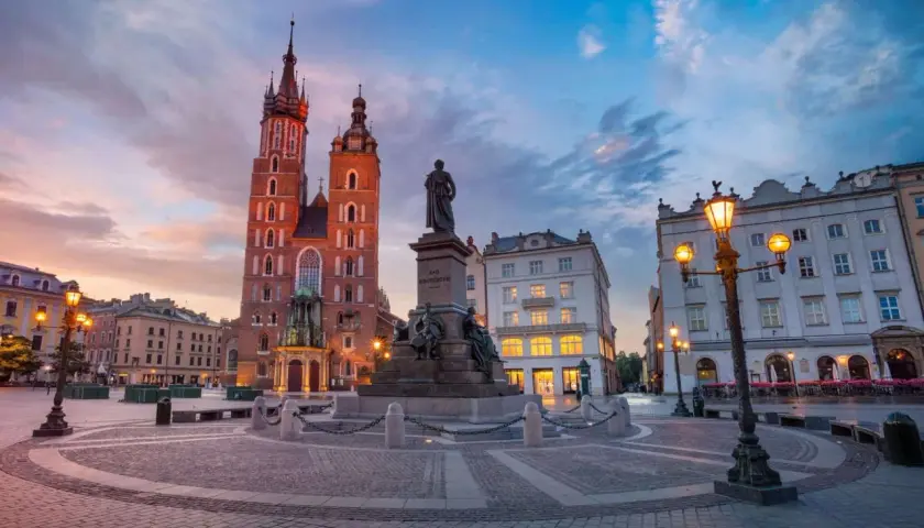Kraków na weekend: Rynek Główny o zmierzchu z Kościołem Mariackim i pomnikiem Mickiewicza. Idealne miejsce na spacer.