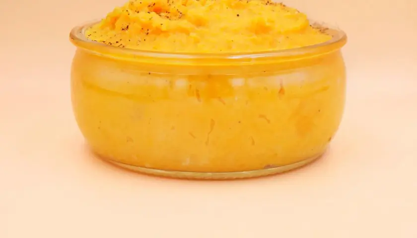 Pyszne, kremowe puree z batata w szklanym naczyniu, posypane świeżo mielonym pieprzem. Idealne jako dodatek do obiadu.