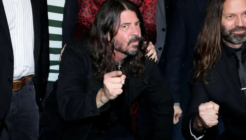 Dave Grohl z zespołu Foo Fighters wskazuje palcem, otoczony przez członków grupy.