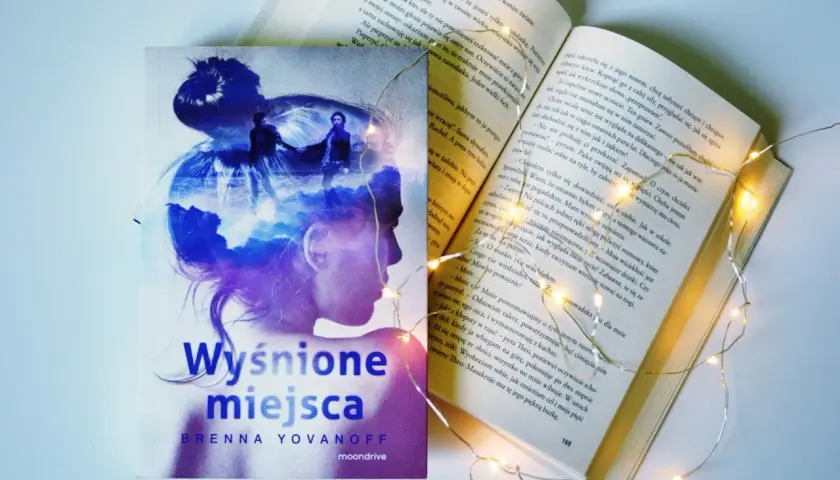 Osoba na okładce książki "Wyśnione miejsca" Brenny Yovanoff, otoczona magicznymi światełkami.