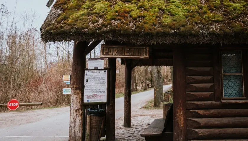 Drewniana portiernia z zielonym, mchowym dachem, zapraszająca do odkrywania atrakcji Biskupina.