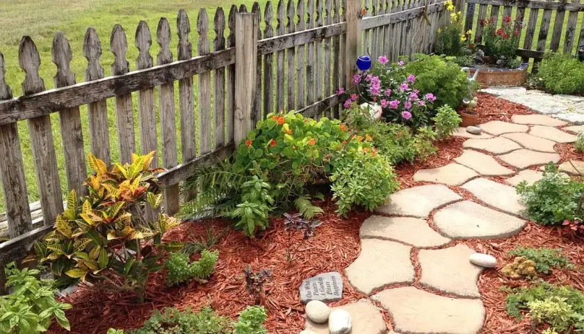 Ein geschwungener Steinweg führt durch einen blühenden Garten. Perfekt, um einen neuen Gartenweg anzulegen.
