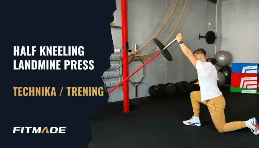 Mężczyzna w pozycji wykrocznej wykonuje ćwiczenie half kneeling landmine press.